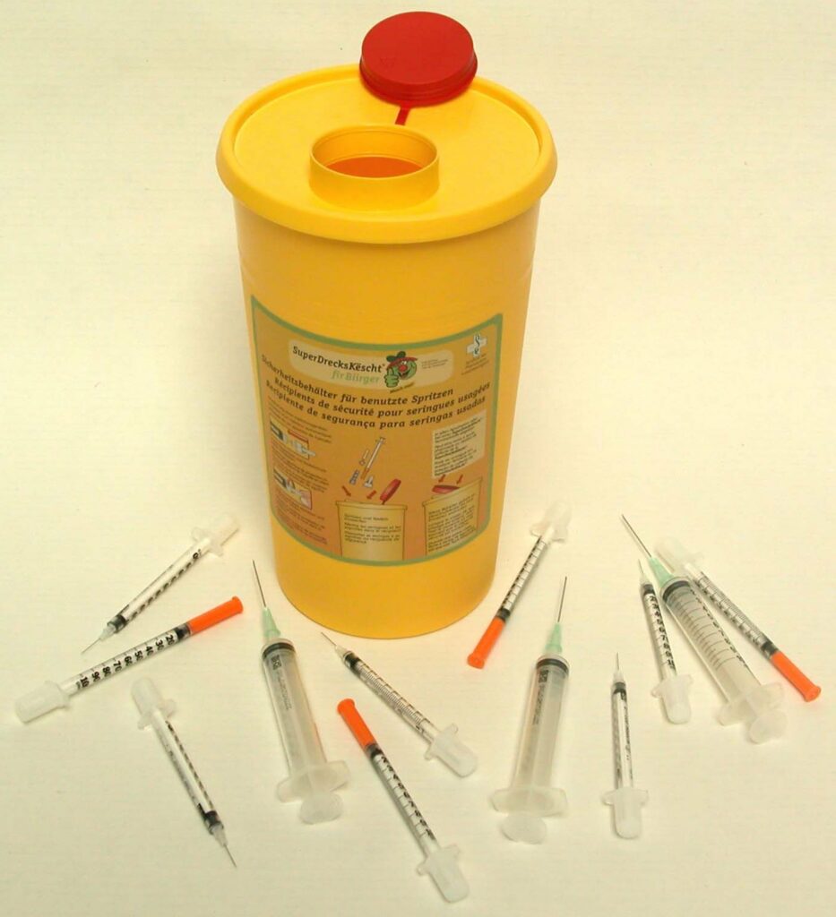 image avec des seringues et le conteneur de la SuperDrecksKëscht pour la collecte des seringues et canules