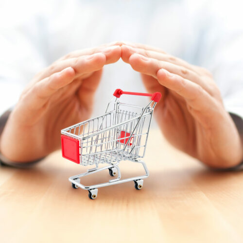 Shopping cart protected by hands. Secure purchase concept.